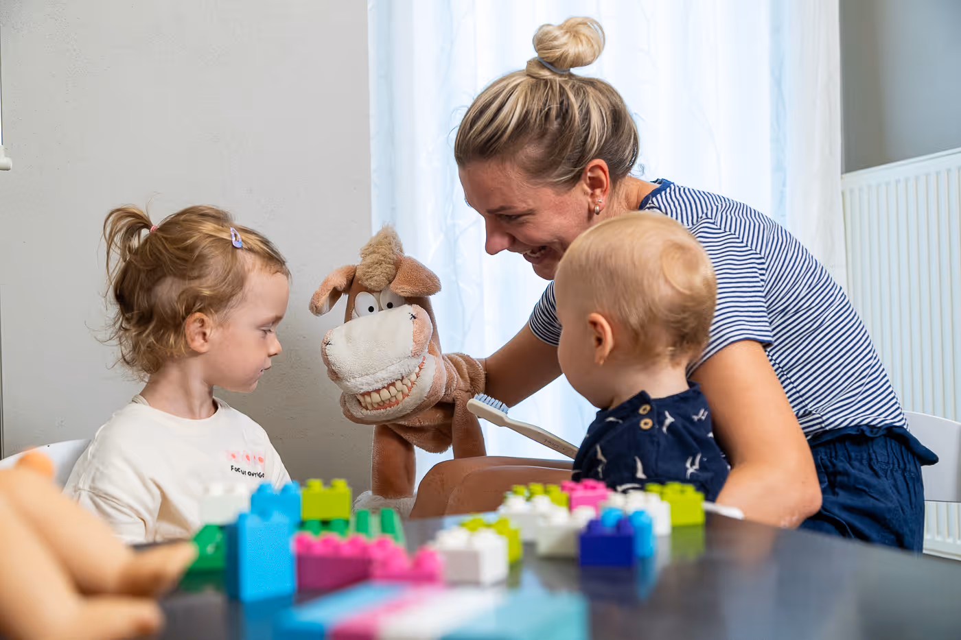 Mutter spielt mit Kindern im Wartezimmer.