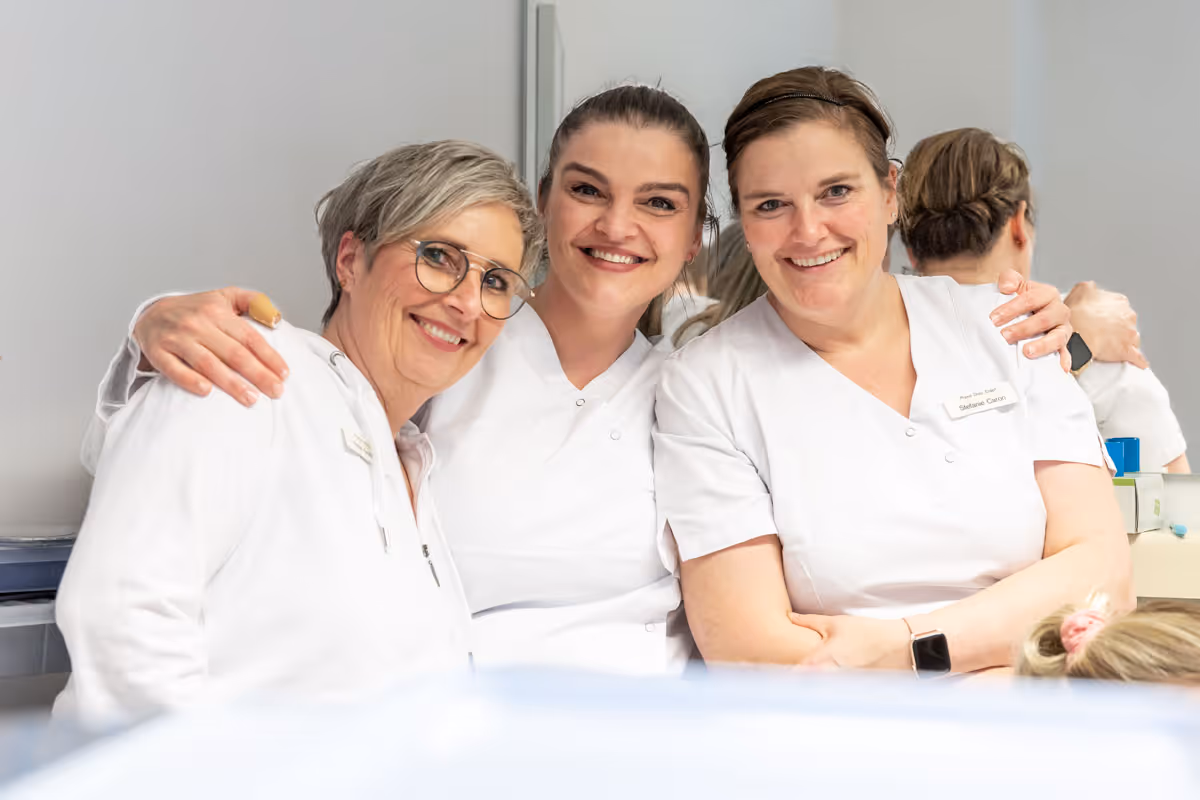 3 Mitarbeiterinnen freuen sich und liegen sich im Arm