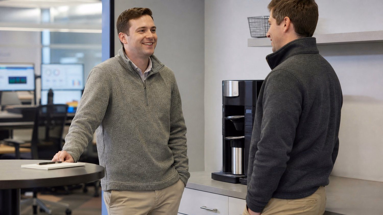 Two Caucasian colleagues in their 30s, wearing casual business attire like grey