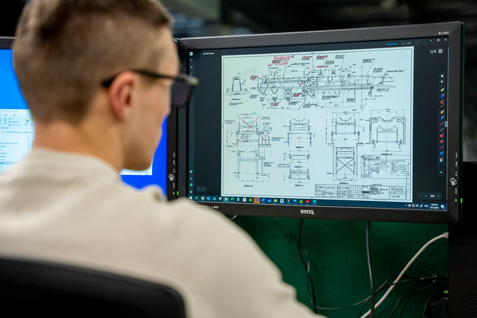 Mechanical engineer controleert werkplaatstekeningen op een computerscherm.