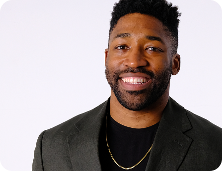 Meech smiling, wearing a dark blazer and a gold chain necklace.