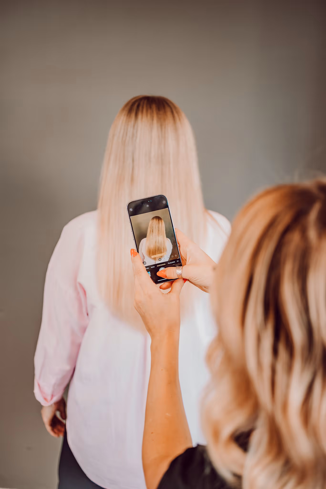 Kampaaja kuvaamassa hiusten leikkauksen lopputulosta