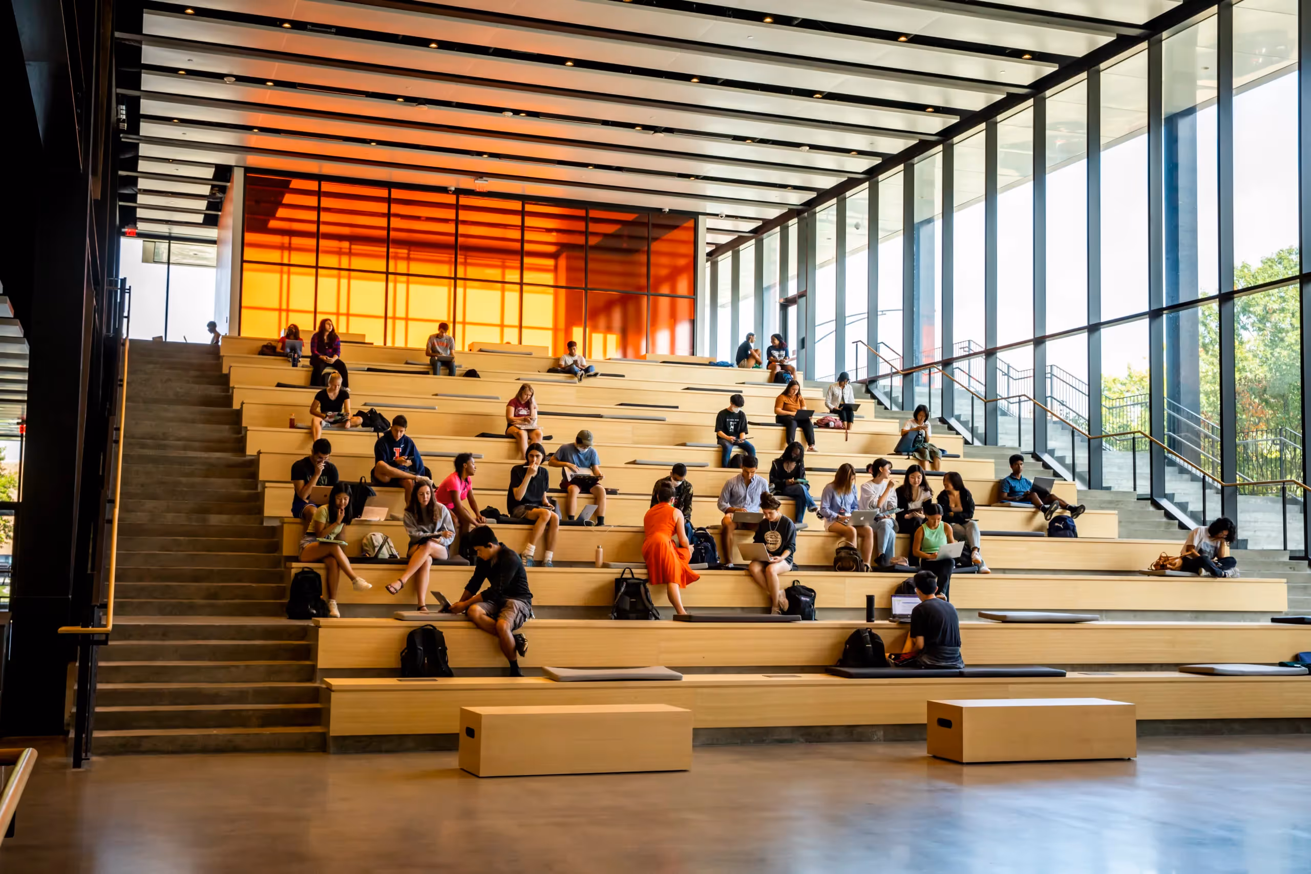 Students on tiered wooden bleachers in atrium