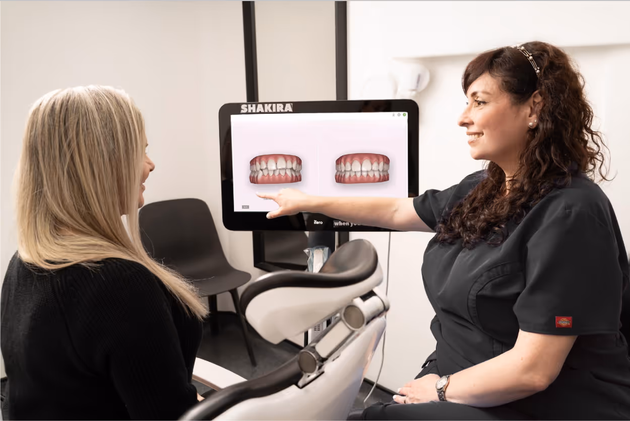 Female dental professional showing a patient digital images of teeth on a screen.