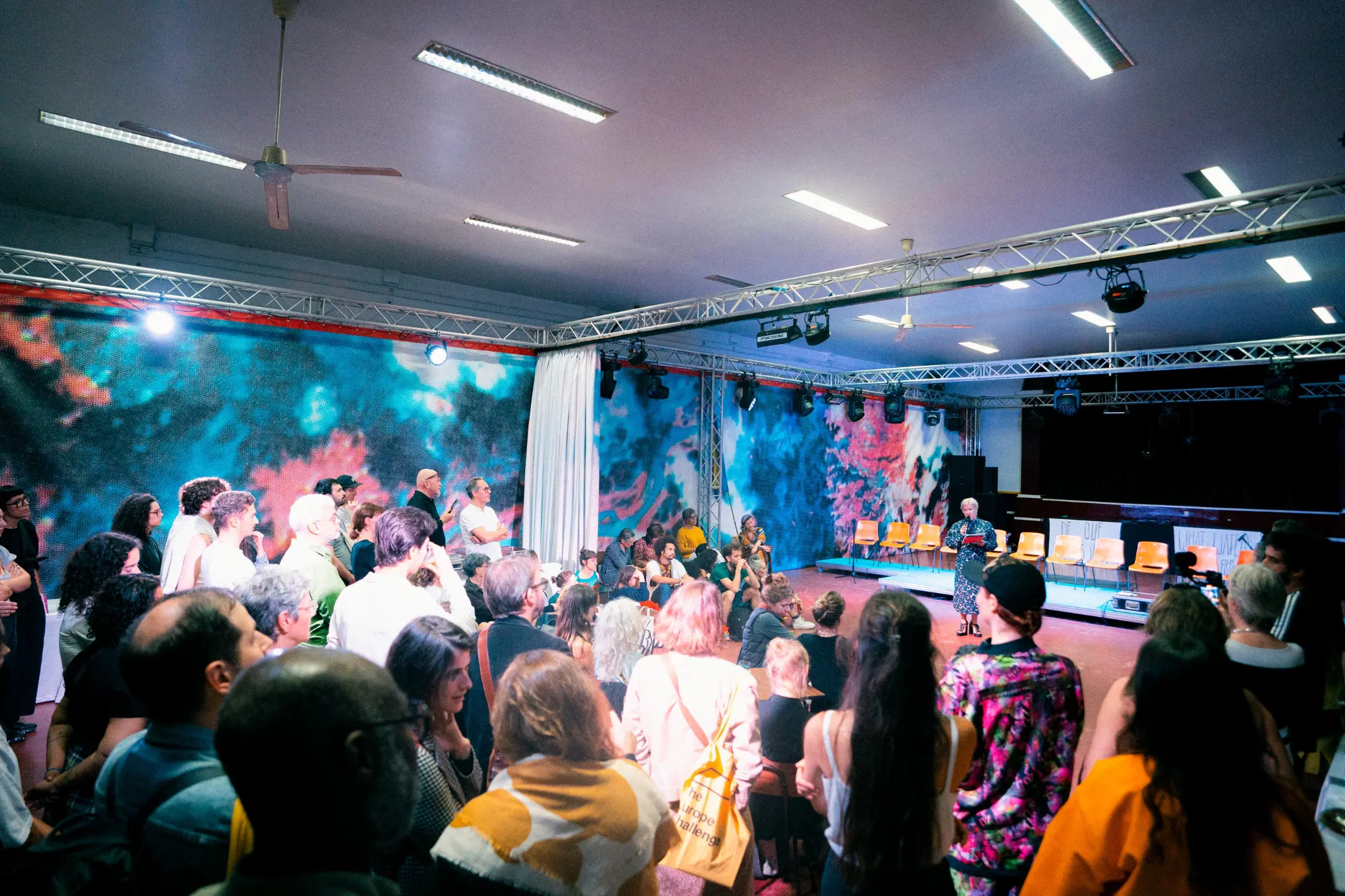 People listening to a female speaker on stage