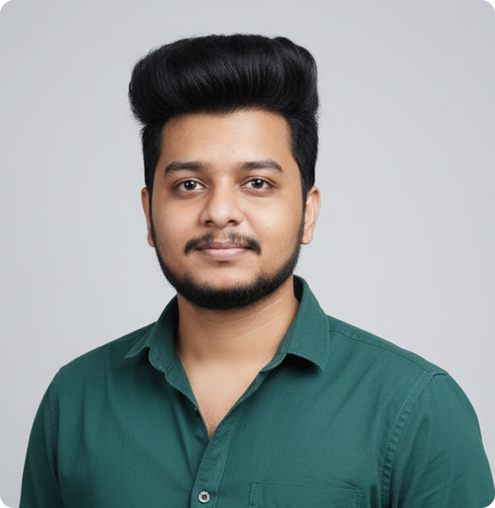 Young man with styled black hair, a short beard, and a dark green button-up shirt, posing against a plain light gray background.