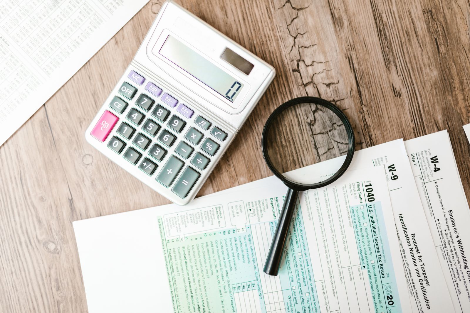 Calculator, magnifying glass and paperwork on a desk