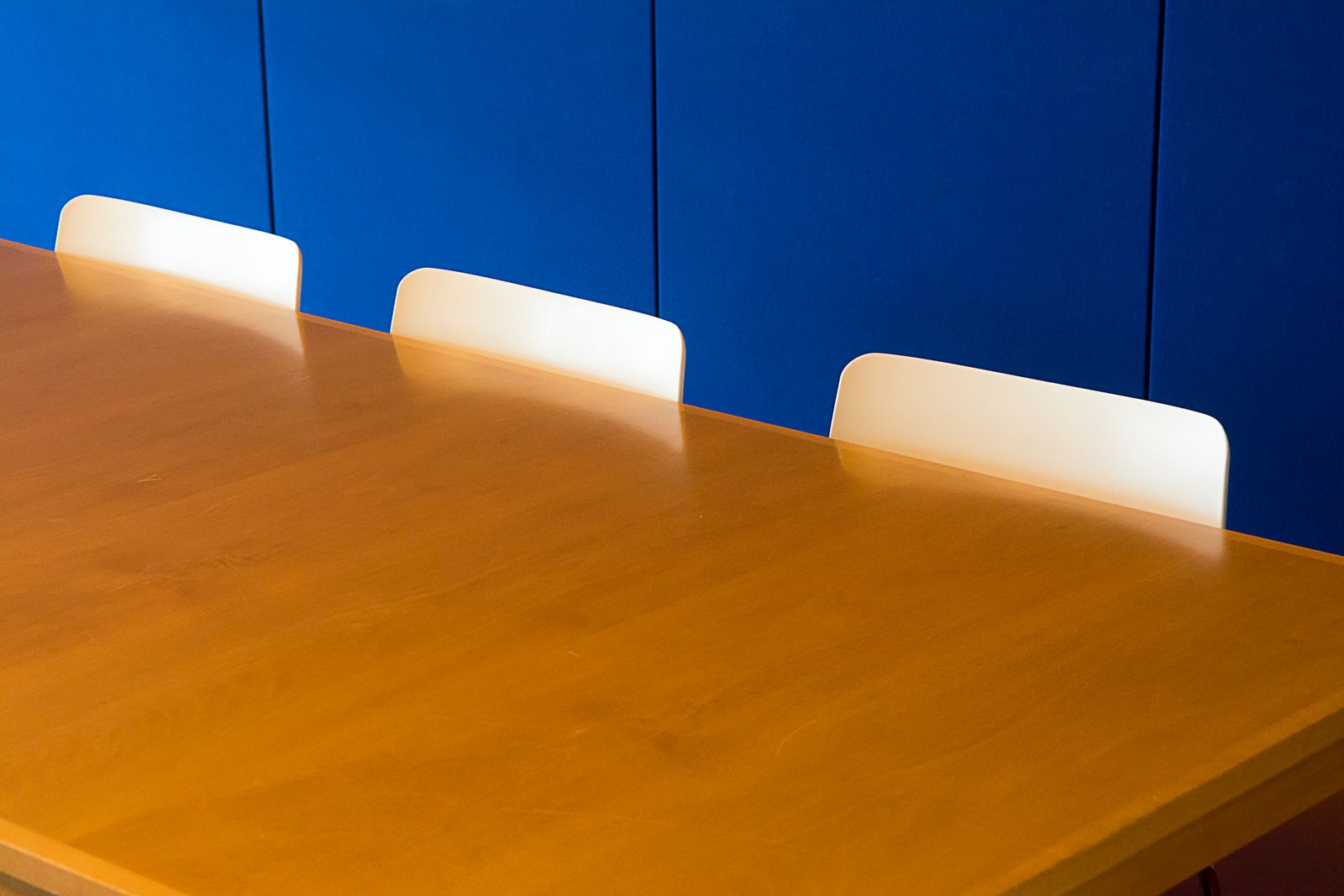 Three chairs at a long wooden table in a meeting room