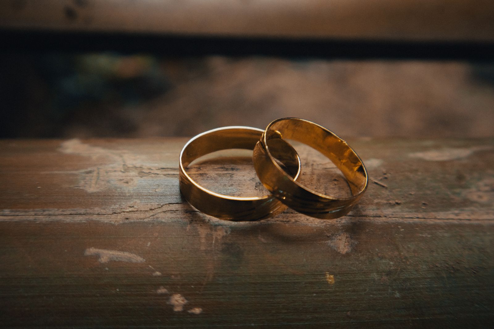 Two gold wedding rings resting on rustic wood