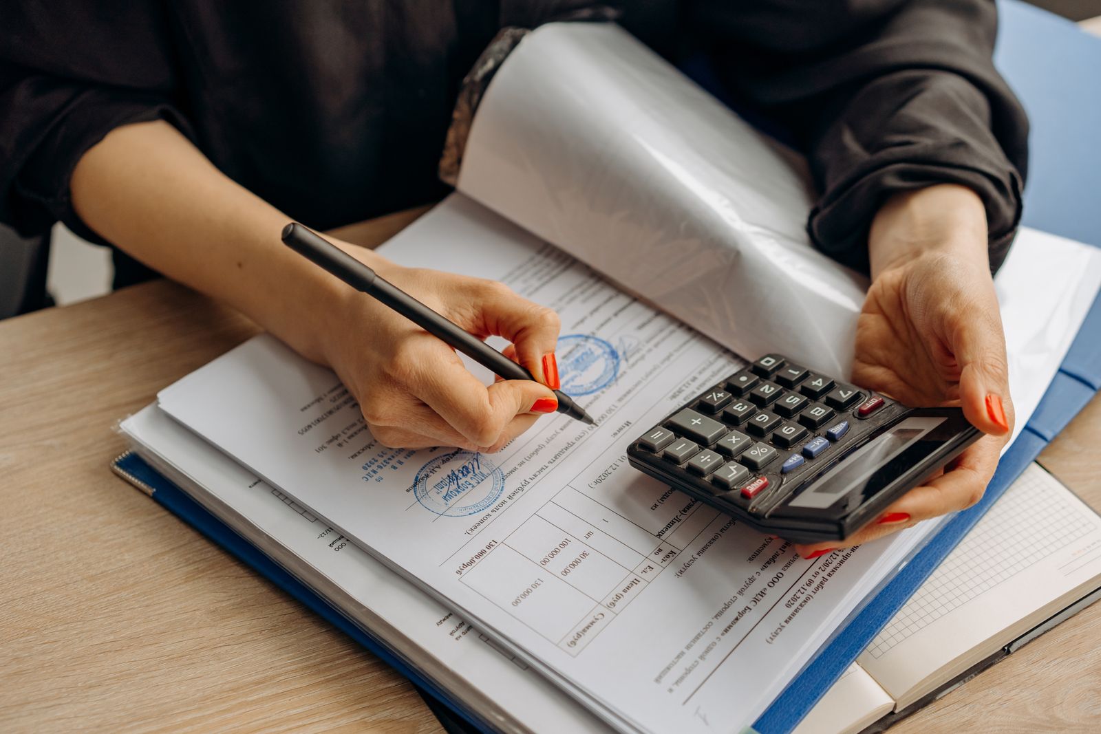 Hands working through a ledger with a calculator