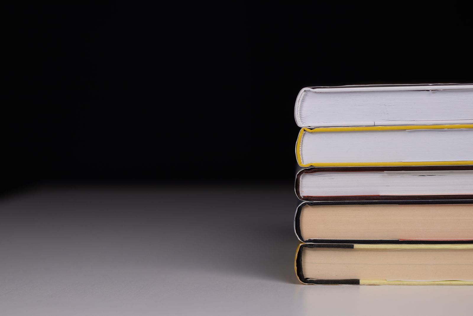 Neat stack of hardback books on a dark background