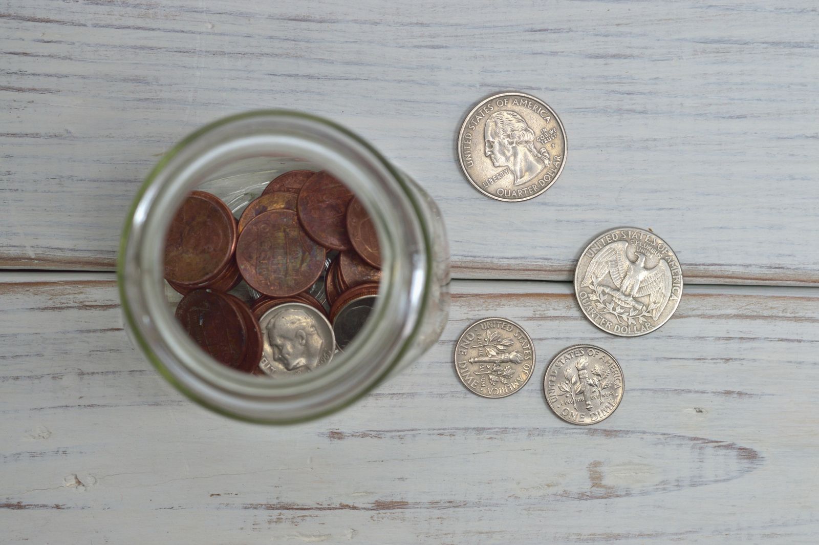 Glass jar of coins on a wooden table
