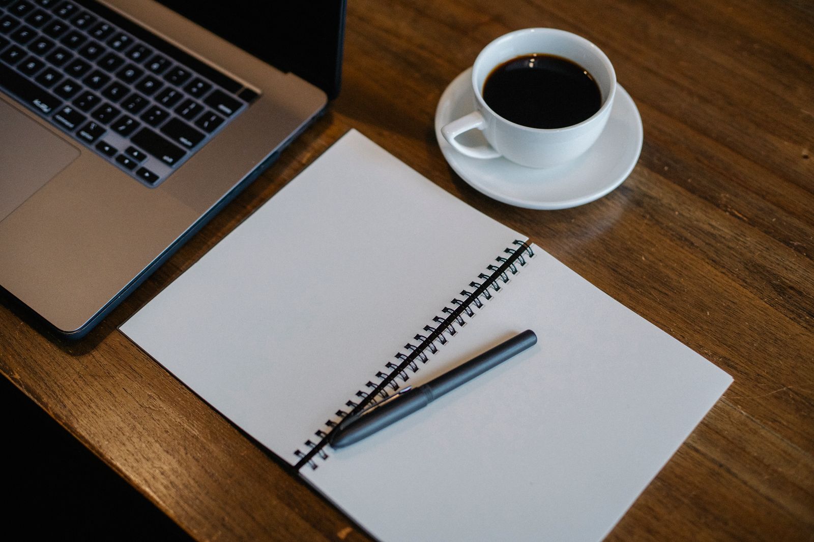 Laptop, notebook and a cup of coffee on a desk
