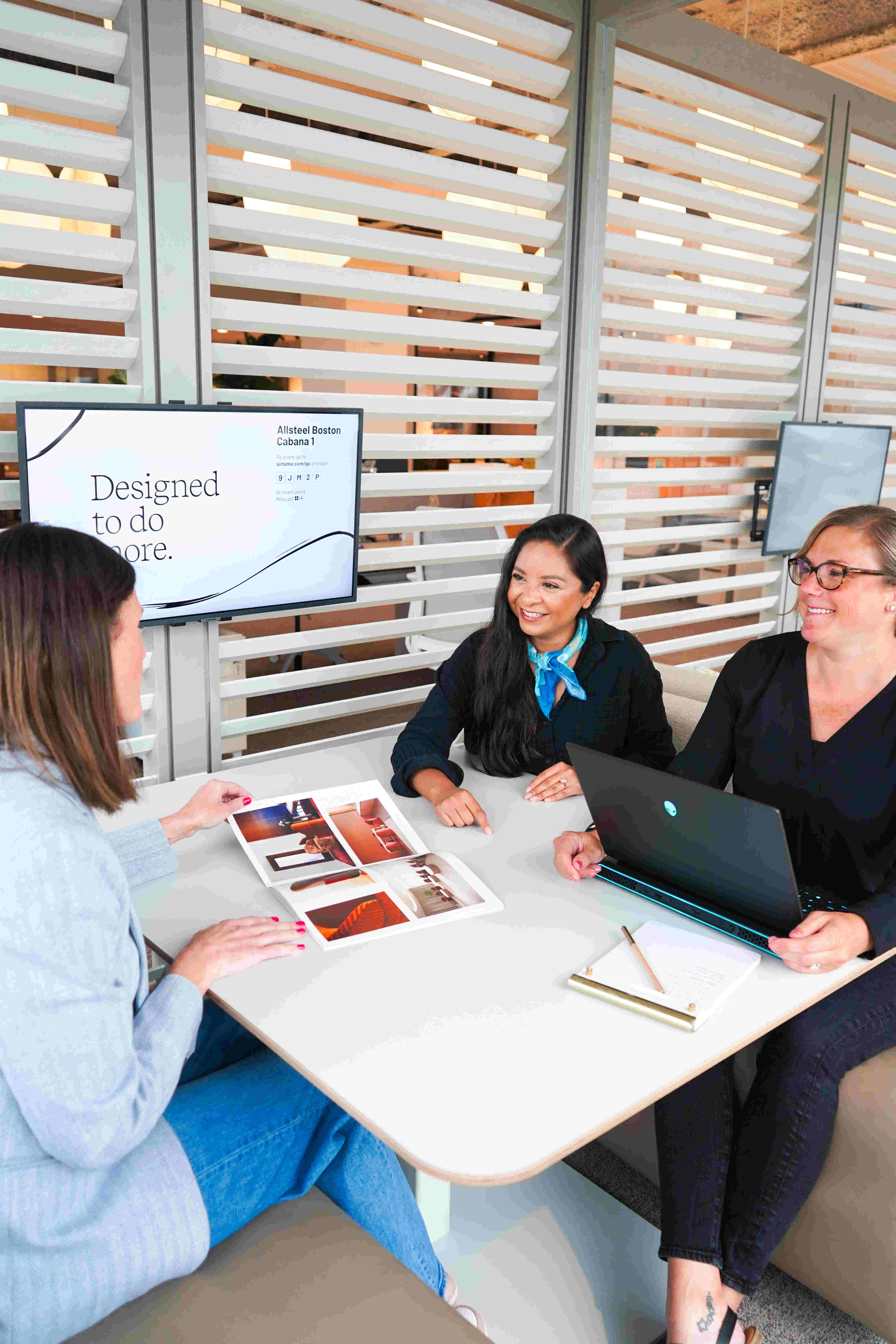 Three women sitting at a booth smiling