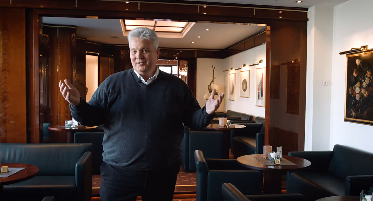 Älterer Mann gestikuliert in einem elegant eingerichteten Café oder Restaurant