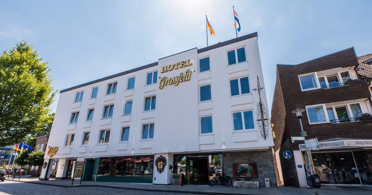 Weißes Hotel Großfeld mit Flaggen an sonnigem Tag in Stadtstraße