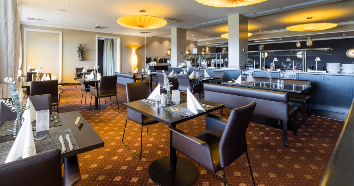 Modernes Restaurant mit gelben Deckenlampen und eleganten schwarzen Stühlen