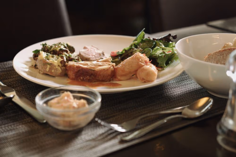 Gegrilltes Fleischgericht mit Salat und Sauce auf einem weißen Teller