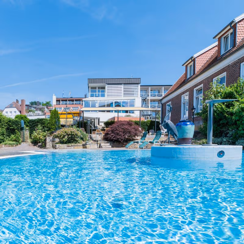 Blauer Swimmingpool mit Häusern und Garten an sonnigem Tag