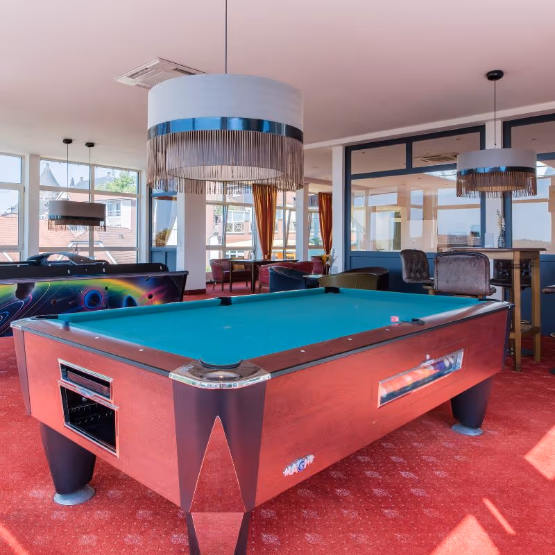 Roter Billardtisch in einem hellen Raum mit modernen Lampen