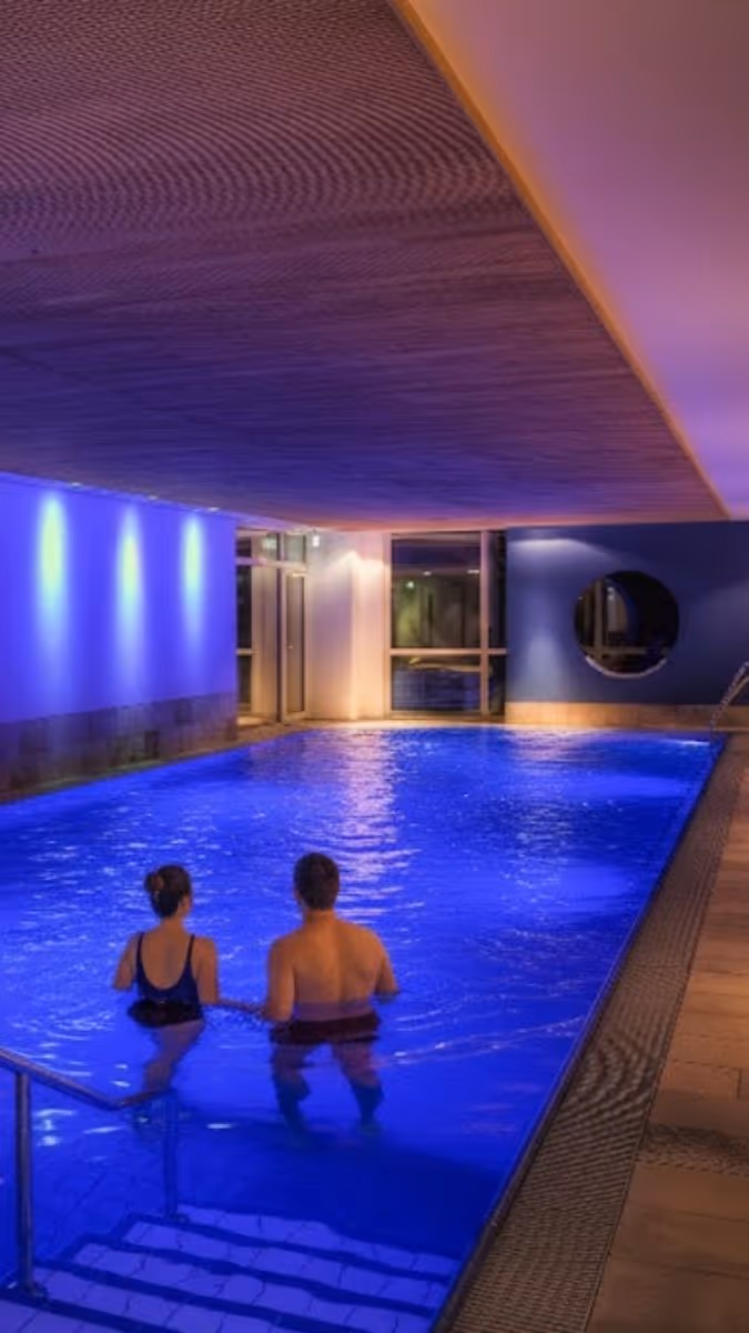 Zwei Personen entspannen im beleuchteten Innenpool mit blauem Licht