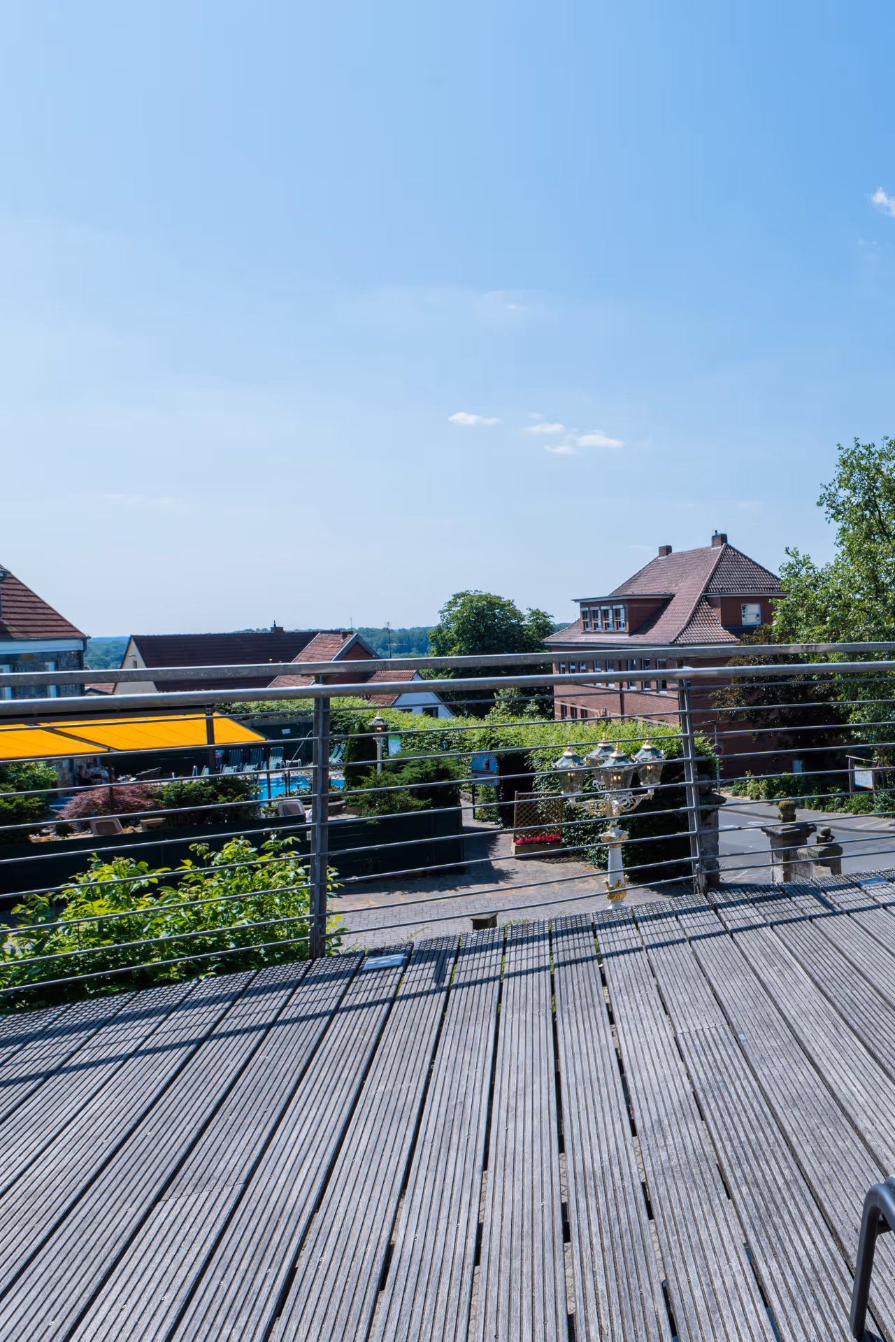 Holzterrasse mit Blick über Dächer und Bäume an einem sonnigen Tag