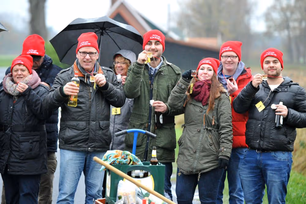 Gruppe mit roten Mützen beim Bierausschank bei regnerischem Wetter draußen