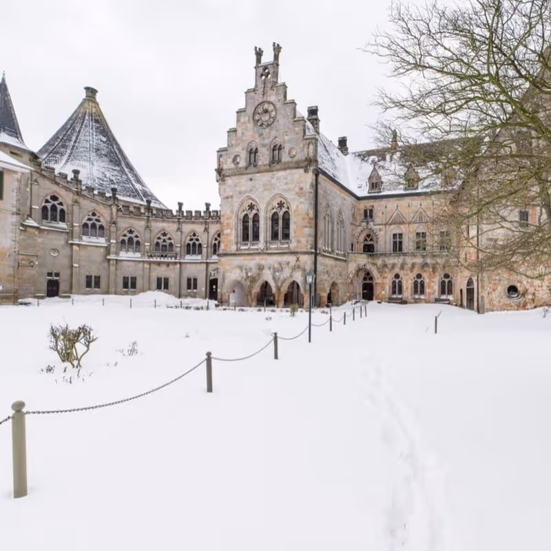 Historisches Schloss mit Uhrturm im verschneiten Winter, gotische Architektur