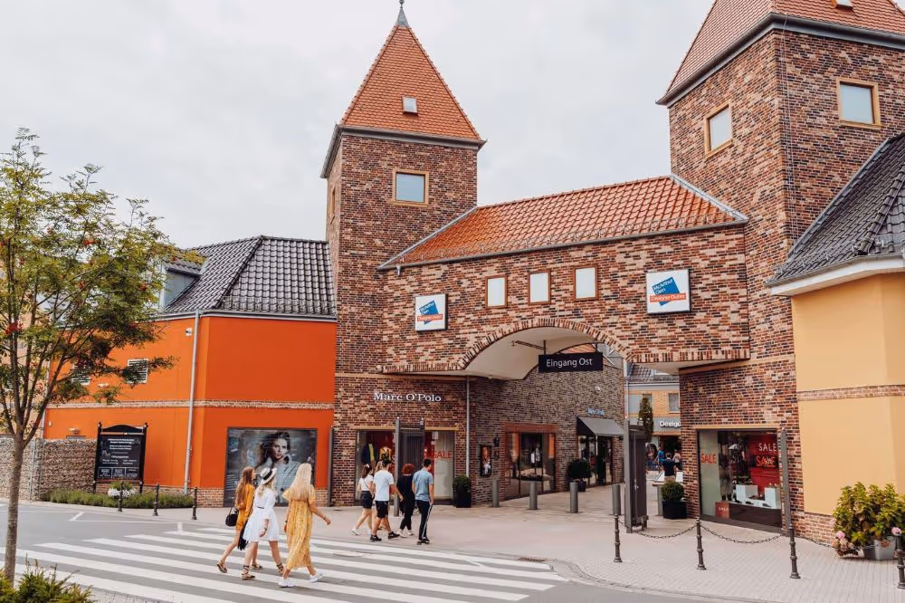 Ziegelsteingebäude mit Einkaufszentrum und Passanten auf Zebrastreifen