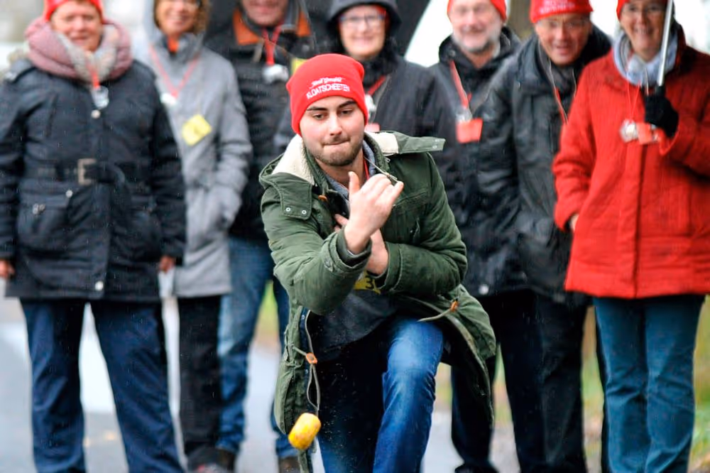 Mann in grüner Jacke wirft Zitrone bei Veranstaltung mit Zuschauern