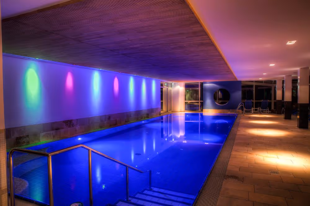 Beleuchteter Innenpool mit bunten Lichtern und moderner Architektur