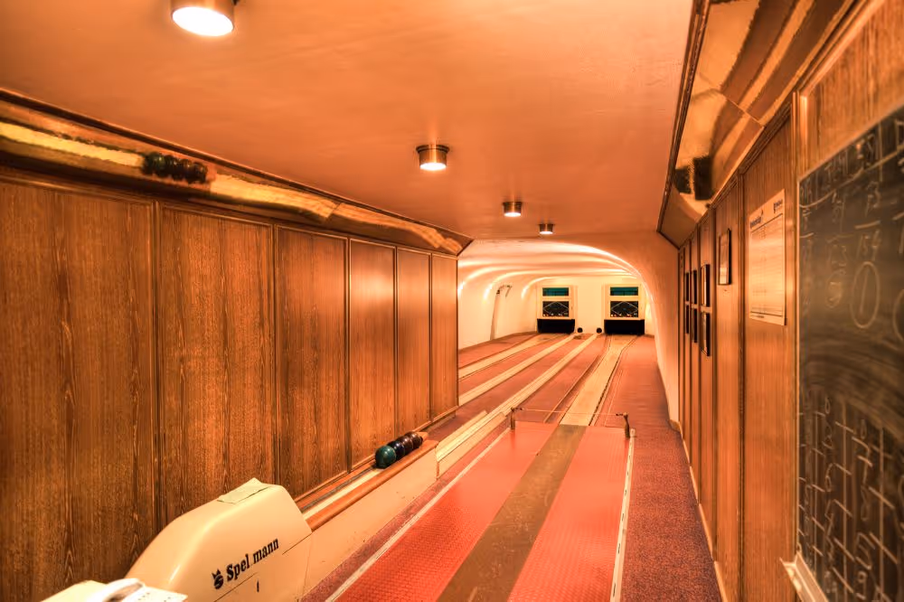 Beleuchtete Bowlingbahn mit Holzvertäfelung und roten Bahnen