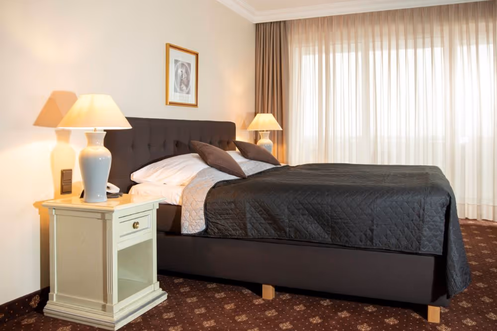 Gemütliches Hotelzimmer mit schwarzer Tagesdecke und warmen Lampen