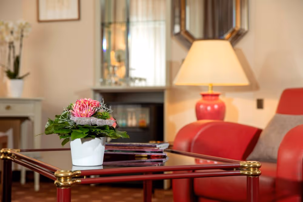 Rote Stehlampe neben Couchtisch mit rosa Blume und Büchern