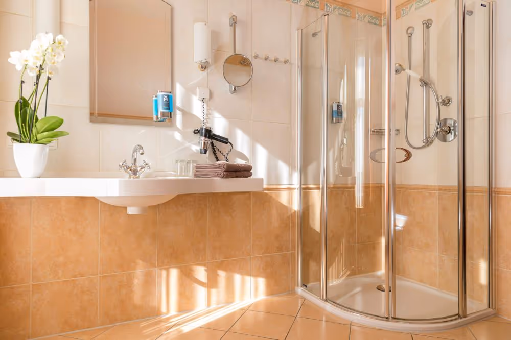 Modernes Badezimmer mit Dusche, Waschbecken und weißer Orchidee