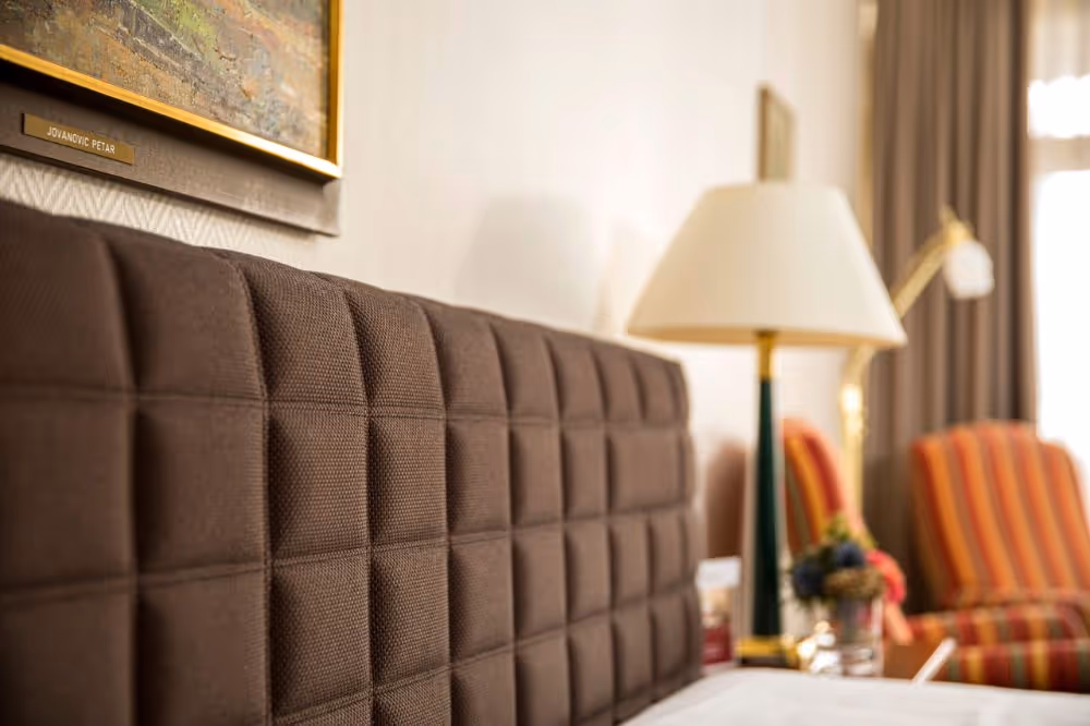 Gemütliches Hotelzimmer mit gepolstertem Kopfteil und warmer Beleuchtung
