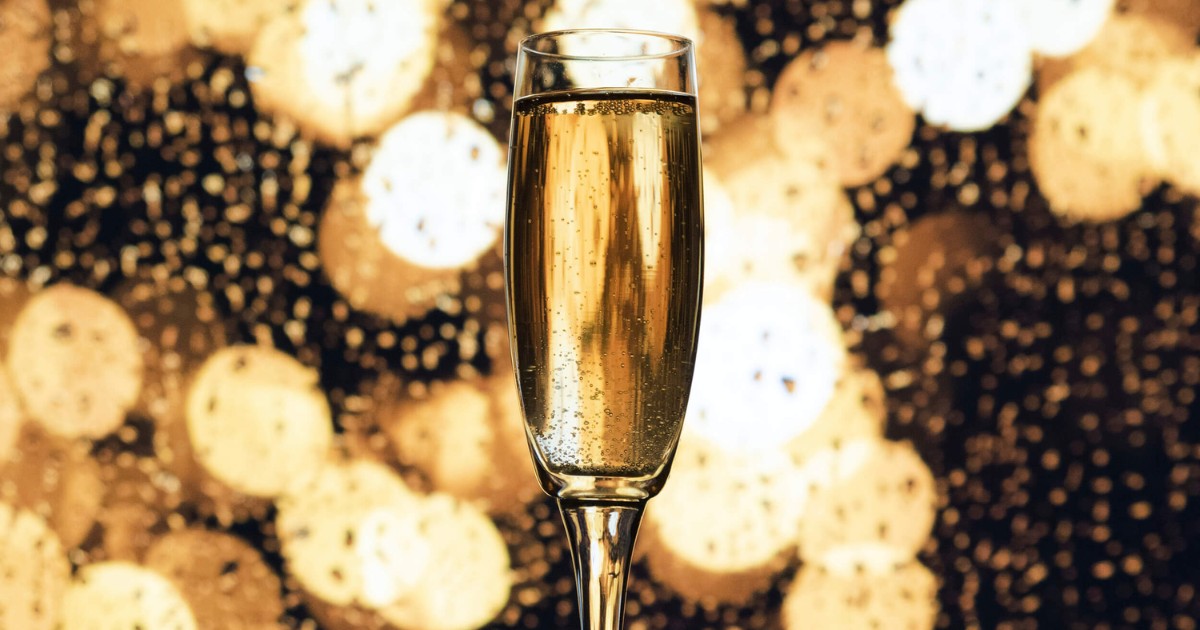 Funkelndes Champagnerglas mit Blasen vor festlichem goldenem Hintergrund