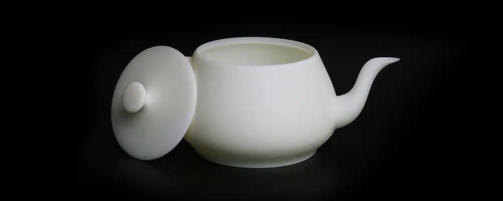 Weiße Teekanne mit abgenommenem Deckel vor schwarzem Hintergrund.