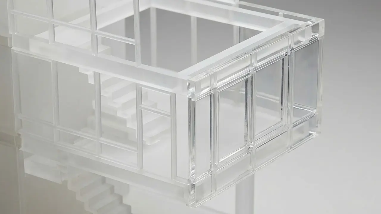 Ein transparentes, modernes Architekturmodell eines Hauses mit Treppe und großen Fenstern.