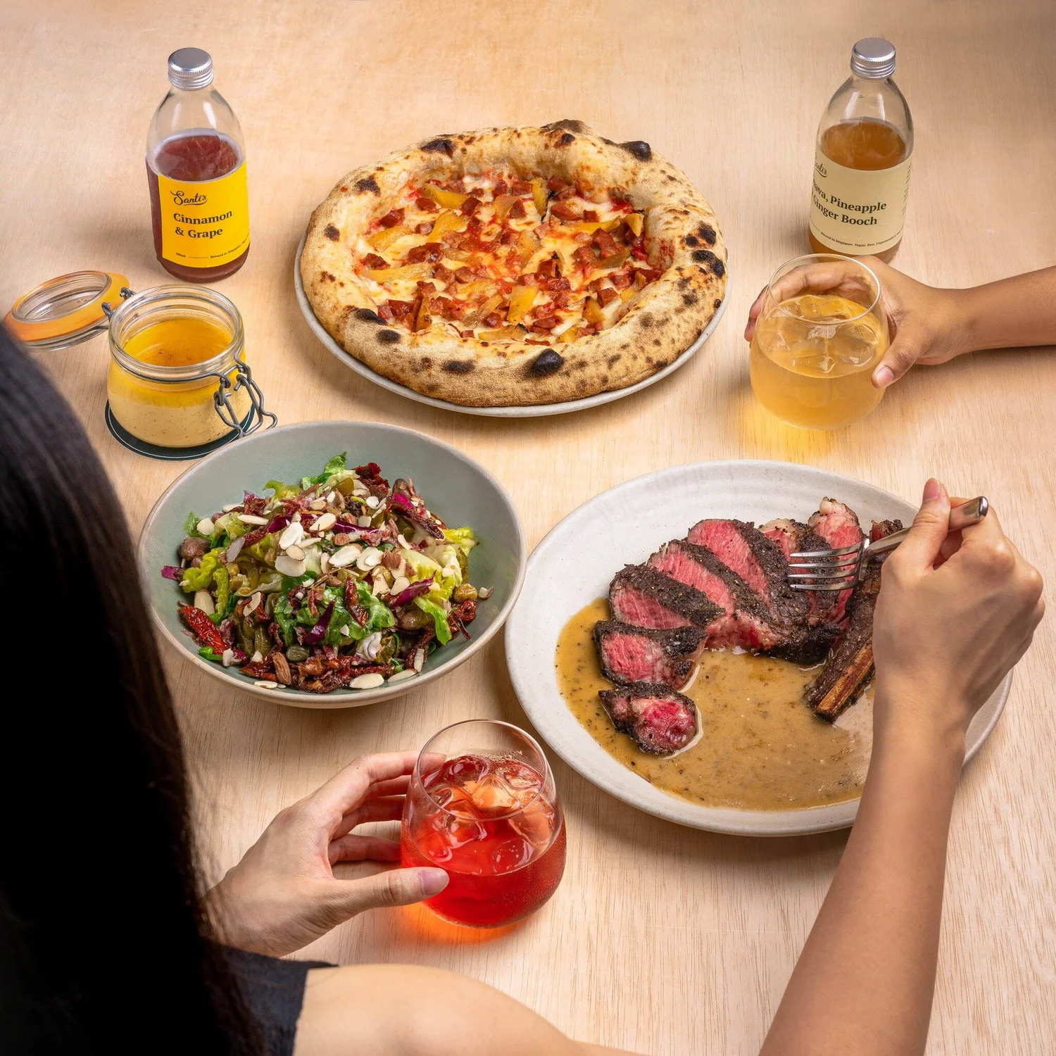 A table at Santi's: sourdough pizza, grilled pork chop, salad and drinks