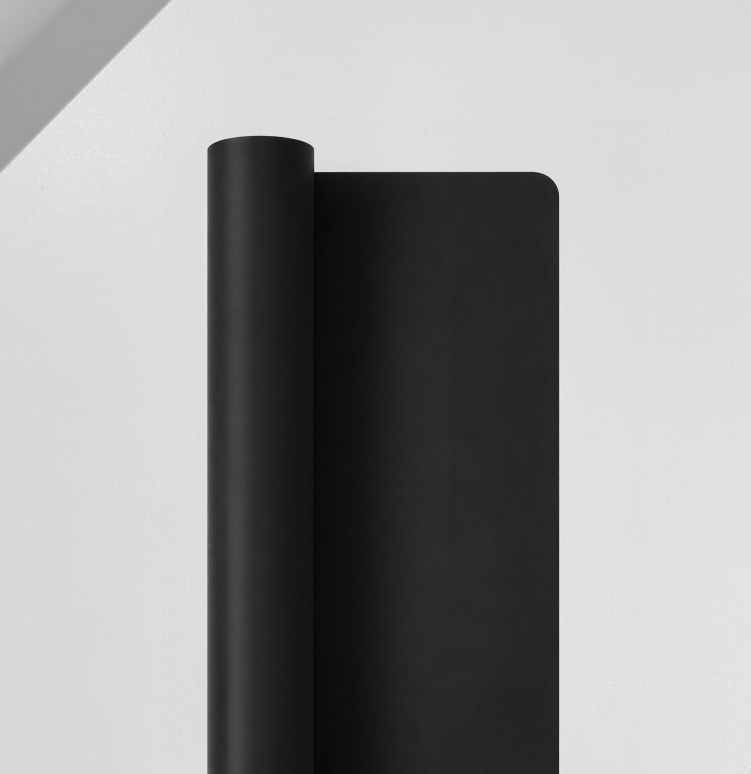 Rolled open black silicone mat with rounded corners on a white surface.