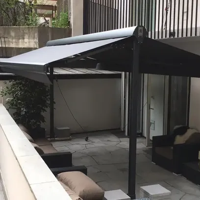 Terrass med mörkgrå terrassmarkis Duo över sittgrupp med fåtöljer och soffor i stadsmiljö i Stockholm.