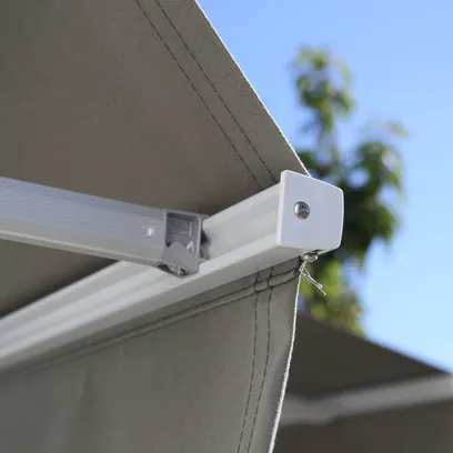 Närmast bild av ett monterat grått markistyg med en vit metallarm F320 och blå himmel i bakgrunden i Stockholm.