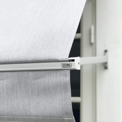 Grå fönstermarkis F320 med vit ram monterad på en vit vägg ovanför ett fönster i Stockholm.