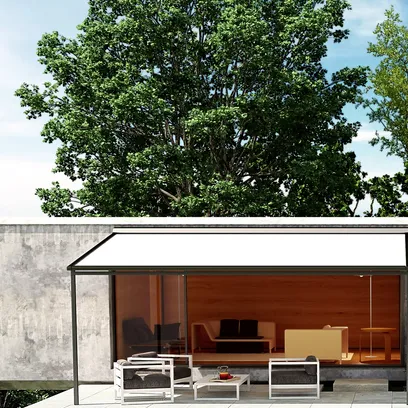 Modern uteplats med vit pergola, gråa soffor och ett lågt bord framför ett hus med stora glasväggar och stor grön trädbakgrund i Stockholm.