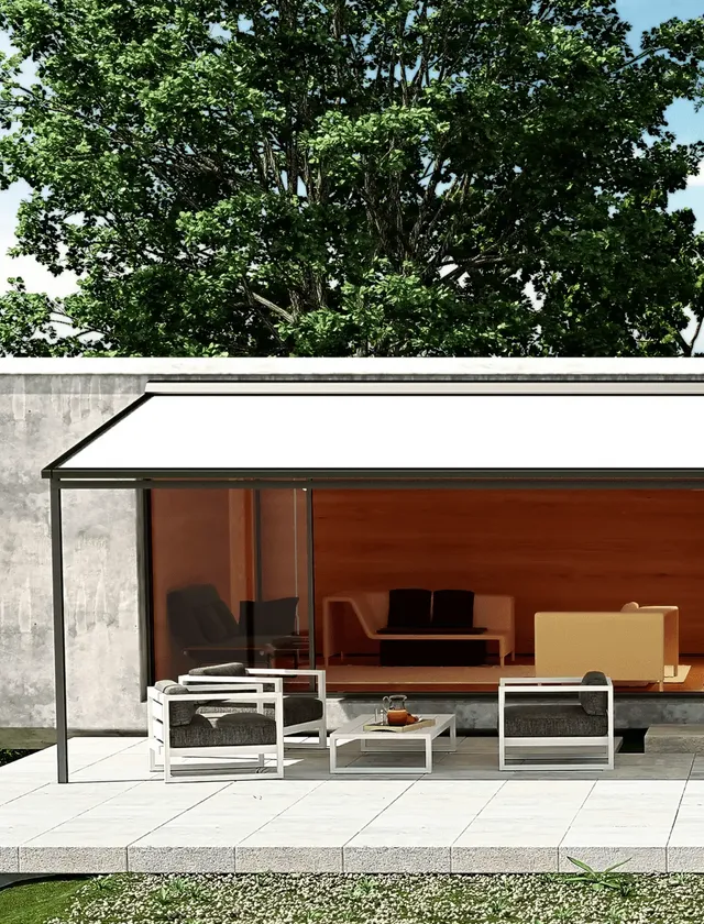 Modern uteplats med vit pergola ovanför två fåtöljer och ett bord på en stenlagd terrass framför ett vardagsrum med stora glasväggar i Stockholm.