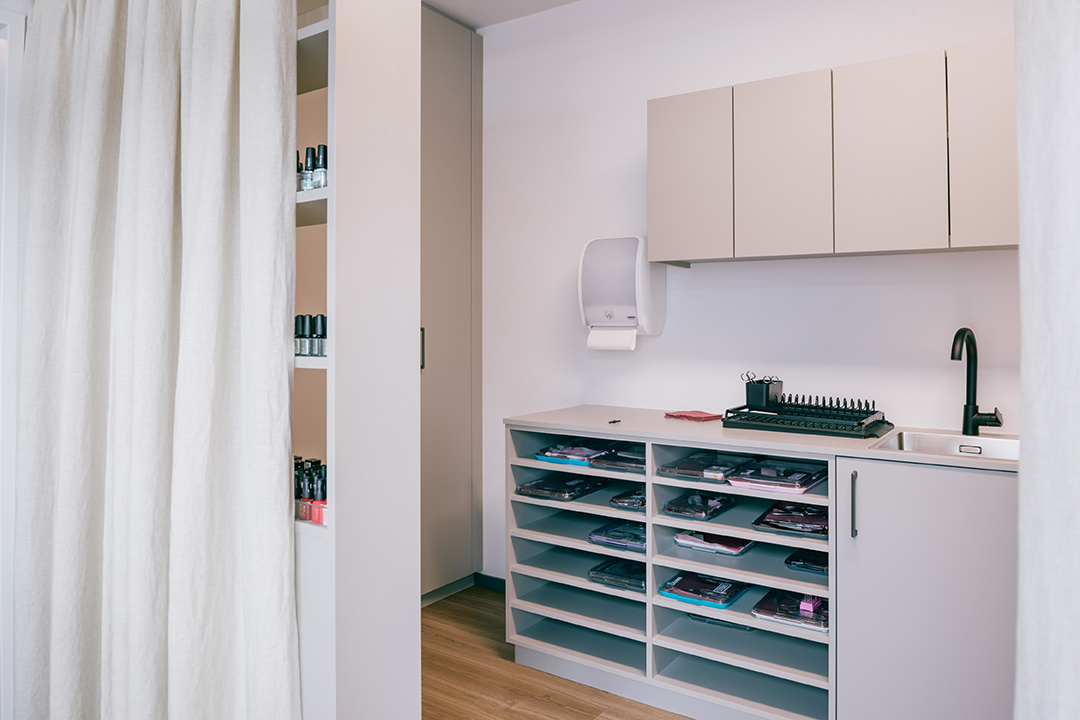 Ordentliche Lagereinheit mit Fächern voller sauber gefalteter Kleidung neben einem Waschbecken und Wandschrank in einem hellen Raum.