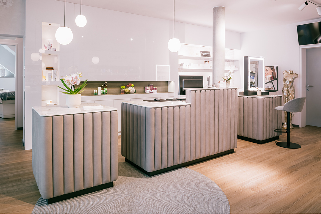 Eleganter Empfangsbereich mit gepolsterten Tresen, hängenden Kugellampen und Holzfußboden.