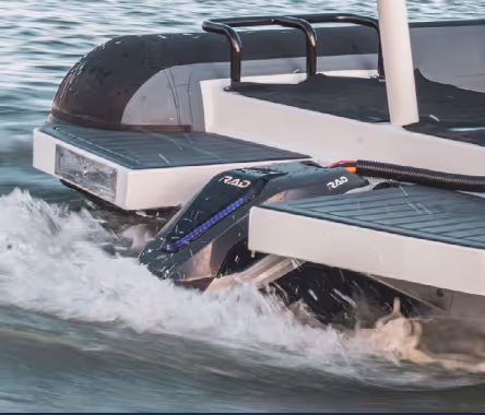 Close-up of a boat motor partially submerged in water, creating splashes as it moves.