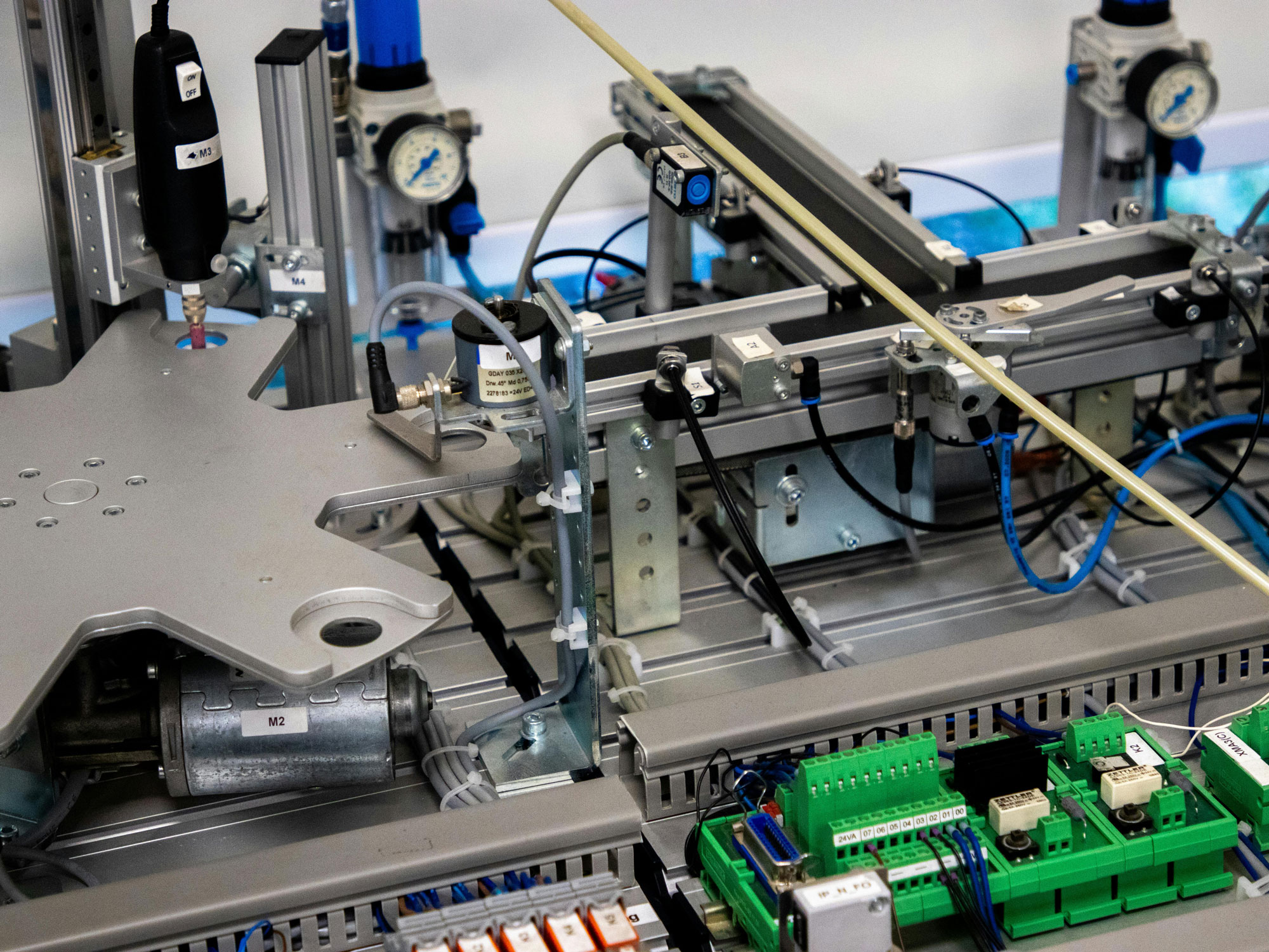 Close-up of an industrial production robot with metal components, wiring, sensors, and green circuit boards mounted on an aluminum frame.